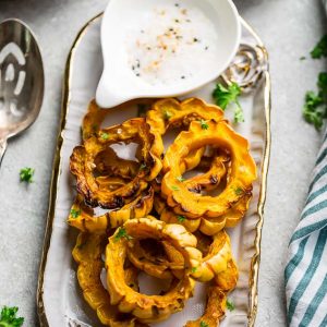 Roasted Delicata Squash on a platter with salt & pepper