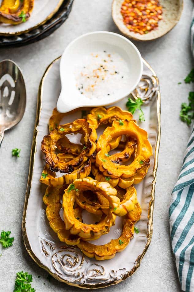 Roasted Delicata Squash on a platter with salt & pepper