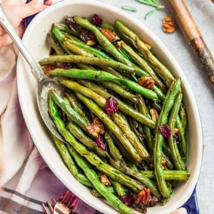 Roasted Green Beans with garlic, balsamic, lemon pepper pecans (and optional cranberries) is the perfect simple recipe to enjoy fresh green beans. This recipe is fancy enough for Thanksgiving, Christmas, or Easter holiday meal, and easy enough for a weeknight side dish! #sidedish #Thanksgiving #christmas #healthy #balsamic #garlic #roasted #vegetables #healthy #keto #paleo #lowcarb