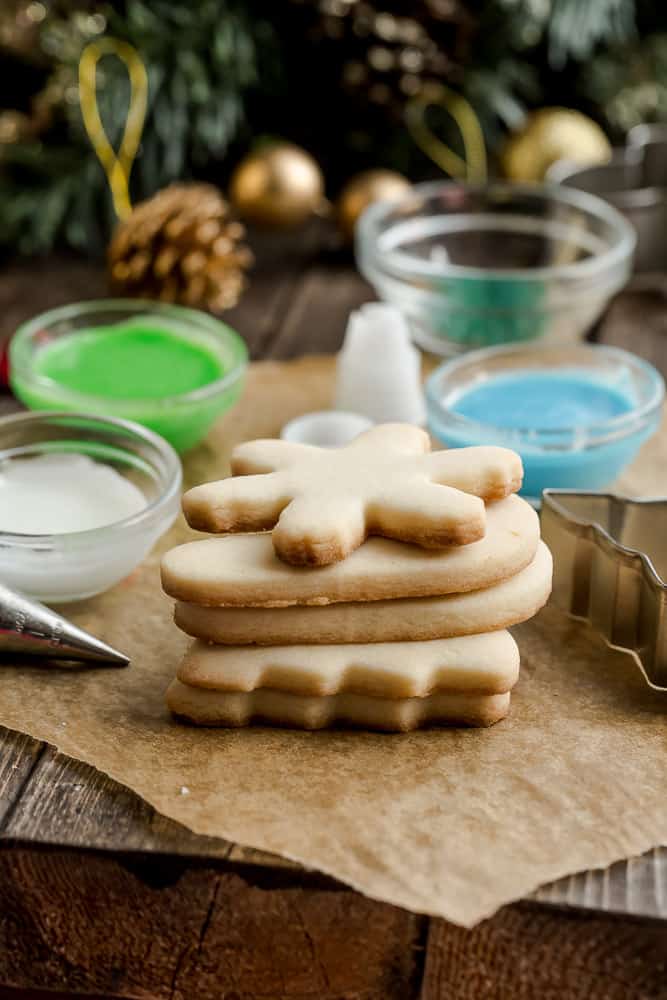 A stack of Keto Sugar Cookies next to bowls of colorful icing