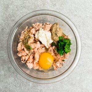 Glass bowl filled with egg, parsley, salmon, and spices.