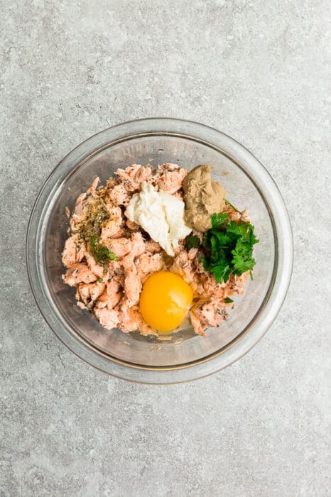 Glass bowl filled with egg, parsley, salmon, and spices.
