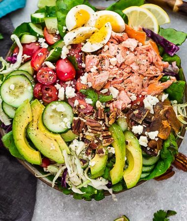 Salmon Cobb Salad is a lightened up twist on the classic Cobb Salad. It’s made with grilled or broiled salmon, cucumber, eggs, tomatoes, avocado, crispy bacon and a creamy and tangy vinaigrette. Low carb, keto , gluten free with Whole 30 & paleo friendly options.