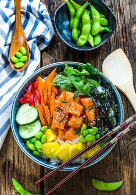 Top view of salmon poke bowl with chopsticks on a wooden background