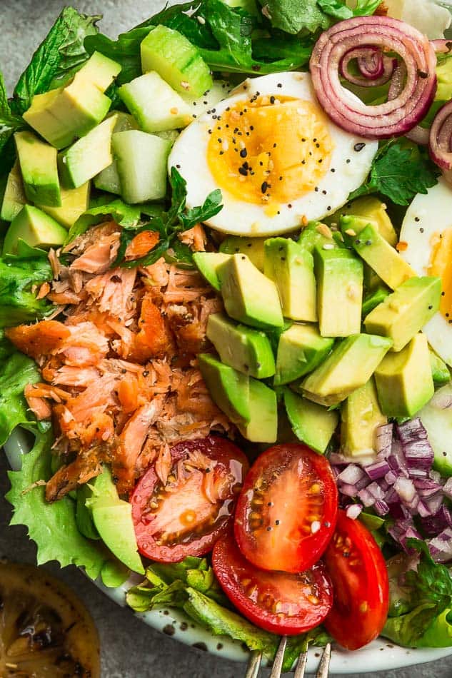 A close-up shot of salmon salad topped with lemon tahini vinaigrette