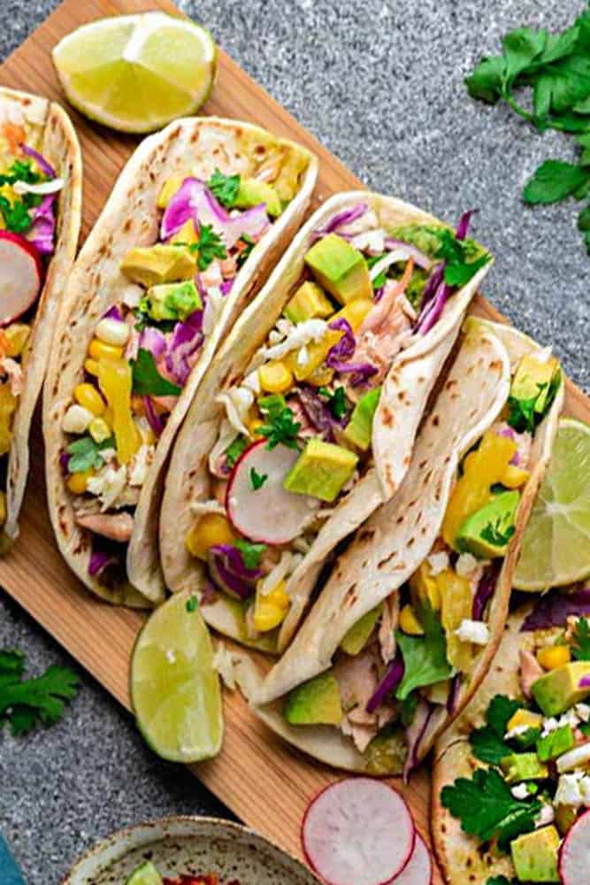 Easy Salmon Tacos - packed with flavor and come together in 30 minutes - perfect for your next Taco Tuesday! Topped with lettuce, red cabbage, corn, pineapple and avocado cream.