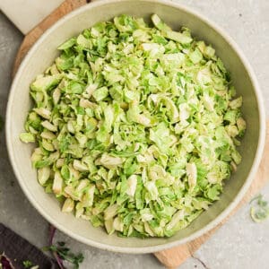Top view of shaved brussels sprouts for brussels sprouts salad in a white bowl on a grey background