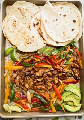 Warm tortillas on a sheet pan with roasted chicken, bell peppers and red onions