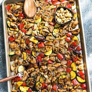 Top view of Sheet Pan Kung Pao Chicken with vegetables and a cup of cashews