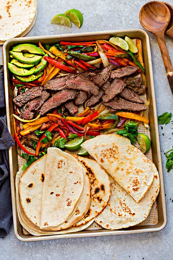 Steak fajitas made on a sheet pan with vegetables and tortillas.