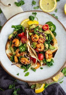 Top view of 2 paleo shrimp tacos on a white plate on a grey background