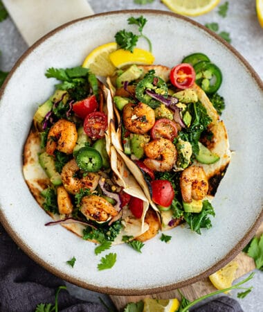 Top view of 2 paleo shrimp tacos on a white plate on a grey background