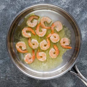 Top view of cooked shrimp in a stainless steel pan on a grey background