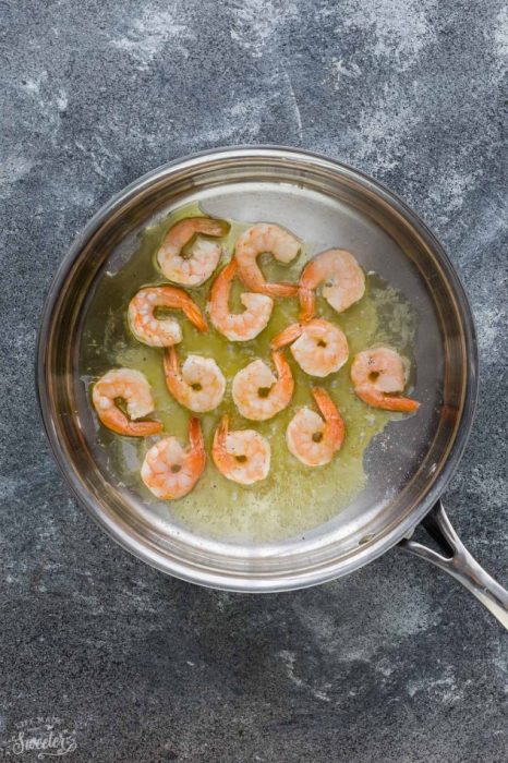 Top view of cooked shrimp in a stainless steel pan on a grey background