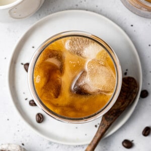 An overhead shot of brewed coffee in a glass with a wooden spoon beside it