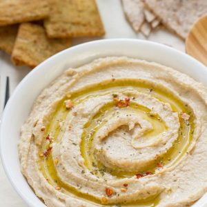 A bowl of homemade hummus in a white bowl with olive oil