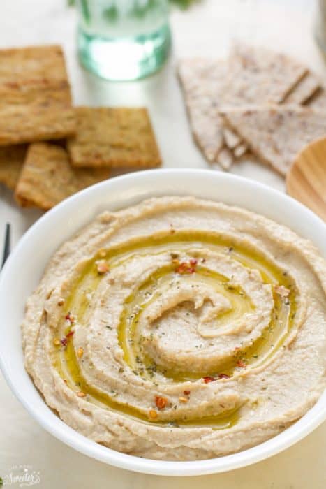 A bowl of homemade hummus in a white bowl with olive oil