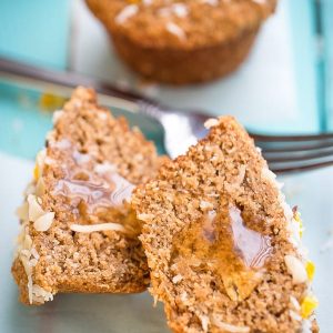 Side view of peach muffin cut in half with some honey on a white plate