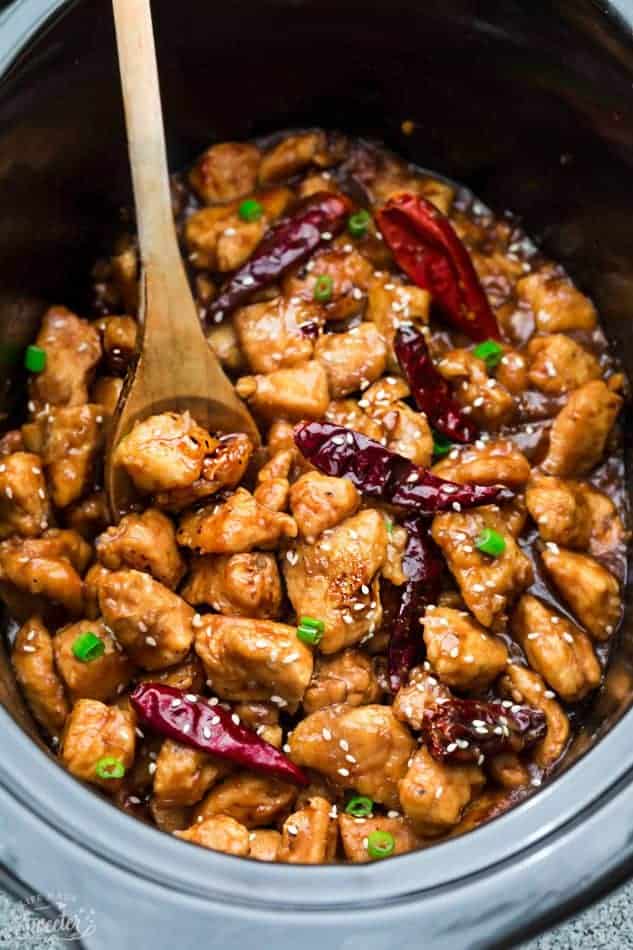 wooden spoon stirring in a slow cooker of paleo friendly General Tso’s Chicken