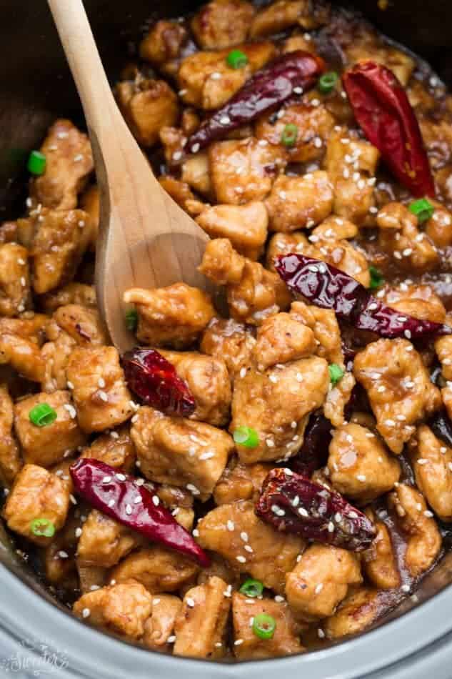 wooden spoon holding pieces of General Tso's Chicken, made in a crock pot