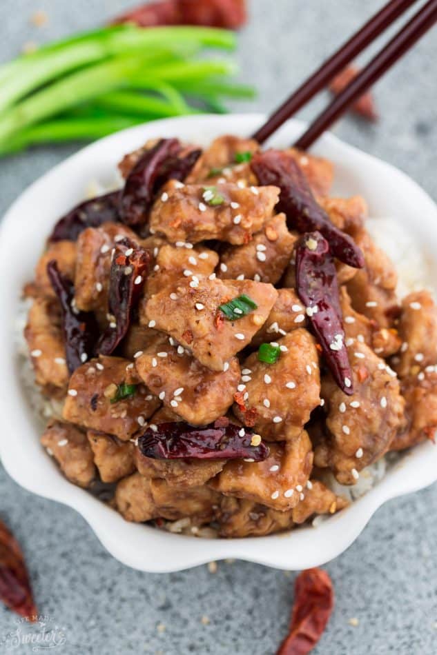 a white scalloped edge bowl of General Tsao's Chicken and a set of chopsticks