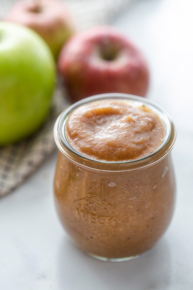 Slow Cooker Apple Butter in a jar in front of a few apples