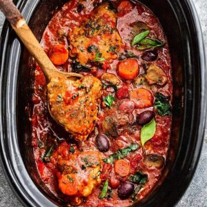 Slow Cooker Chicken Cacciatore being stirred in a crockpot with a wooden spoon