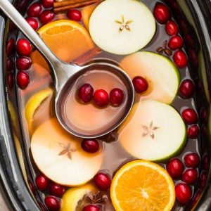Top view of apple cider in a slow cooker with a ladle