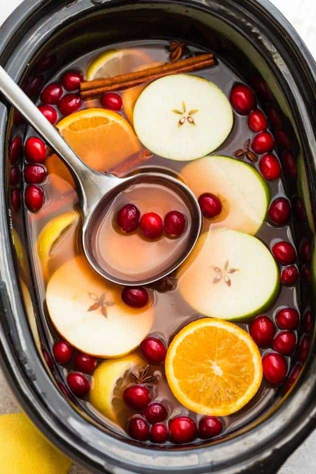 Top view of apple cider in a slow cooker with a ladle