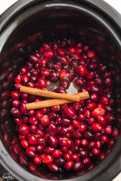 Overhead view of cranberries and cinnamon sticks in a slow cooker