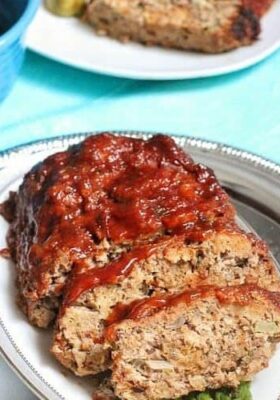 A slow cooker meatloaf cut into slices on a white oval platter
