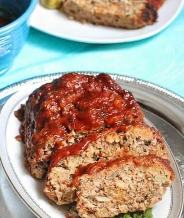 A slow cooker meatloaf cut into slices on a white oval platter