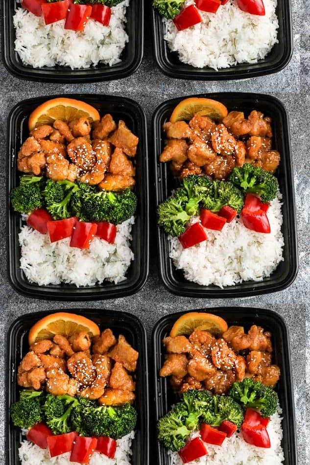 Slow Cooker Orange Chicken in meal prepping containers with broccoli, white rice, orange slices and red bell peppers.