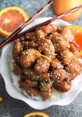 Simple slow cooker Orange Chicken with toasted sesame seeds, sliced carrots and green onions.