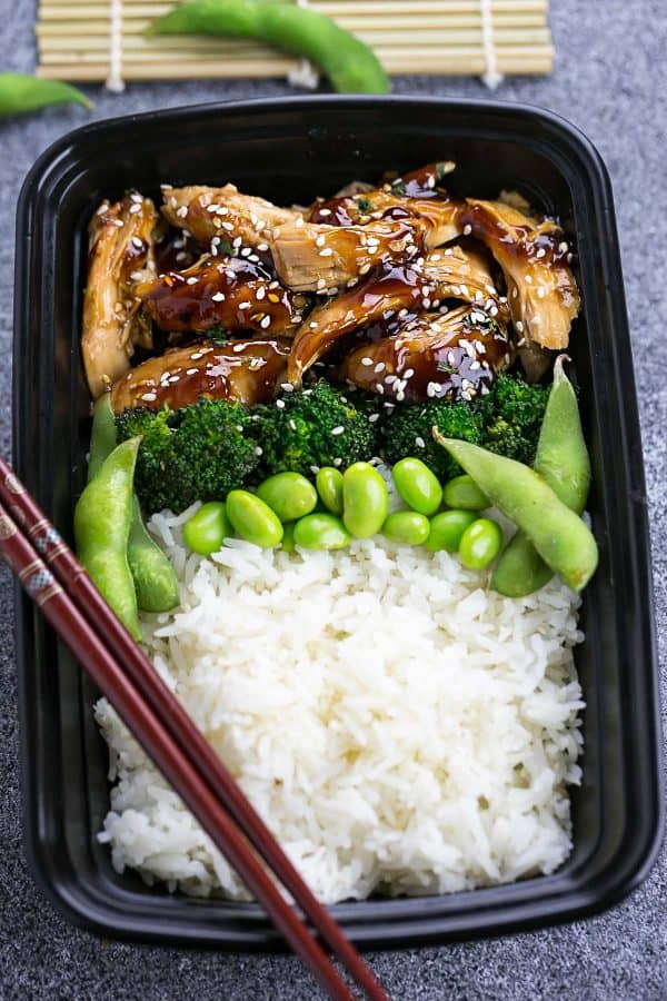 Slow Cooker Chicken Teriyaki with peas,, broccoli and white rice in black take out container with dark red chopsticks.