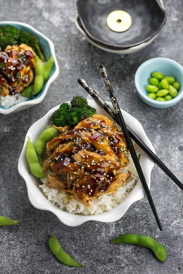 Top view of two bowls of slow cooker teriyaki chicken on grey surface.