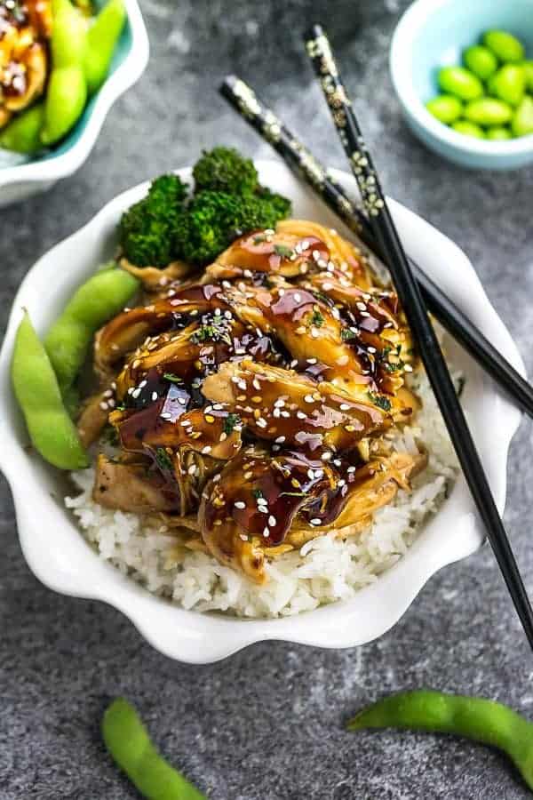 Top view of slow cooker teriyaki chicken on grey surface with chopsticks. 