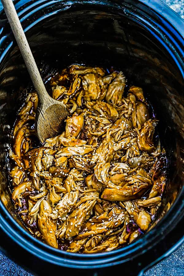 a crockpot with Chicken in teriyaki sauce with a wooden spoon.