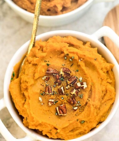 Top view of sweet potato mash in a white bowl with a gold spoon