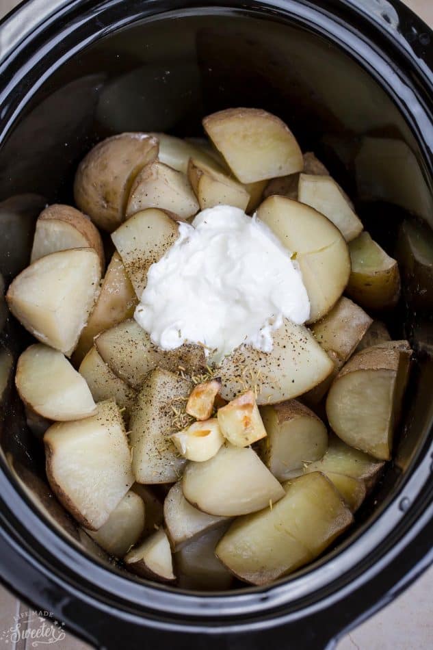Top view of cut Russet potatoes and garlic in a 6 quart slow cooker