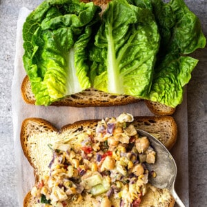 Building a chickpea salad sandwich on a piece of gluten free bread with lettuce
