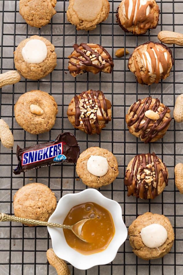 Top view of Snickers Thumbprint Cookies with a bowl of caramel sauce on a cooling rack