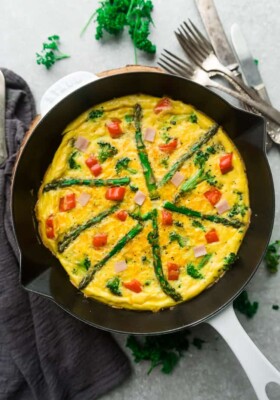 Top view of Keto Frittata with Asparagus, Tomatoes and Ham in a White Cast Iron Skillet Pan