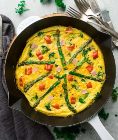 Top view of Keto Frittata with Asparagus, Tomatoes and Ham in a White Cast Iron Skillet Pan