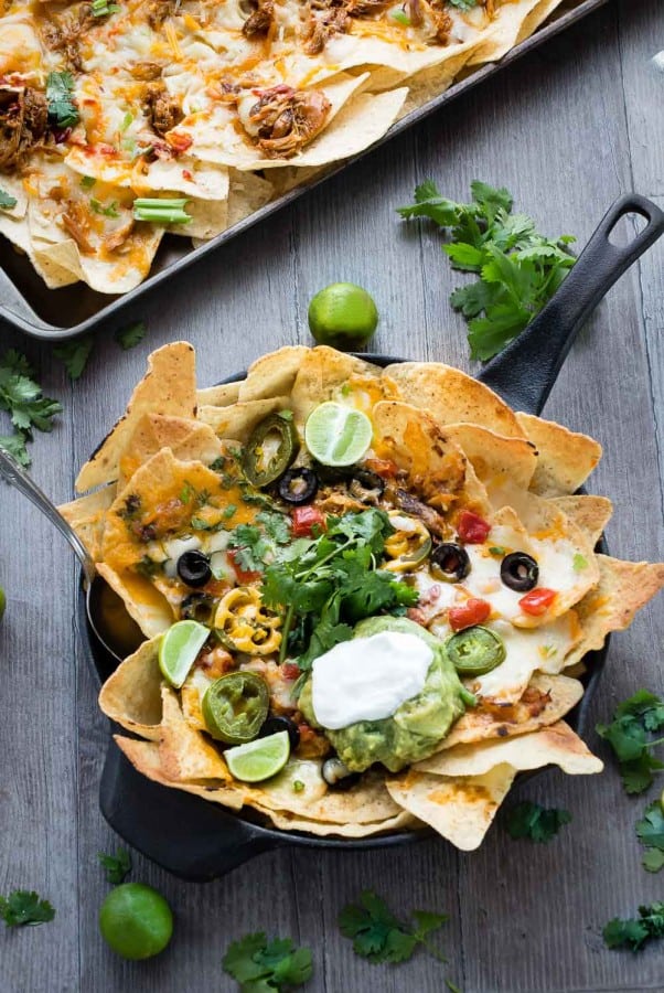 Sriracha Honey Chicken Nachos in a cast-iron skillet and on a baking sheet