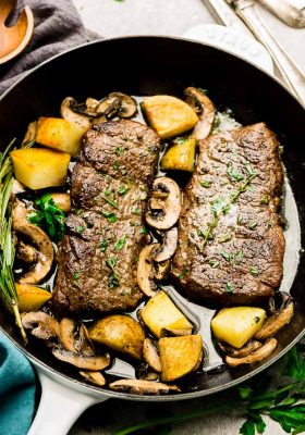 Top view of steak and Potatoes in a white cast iron pan