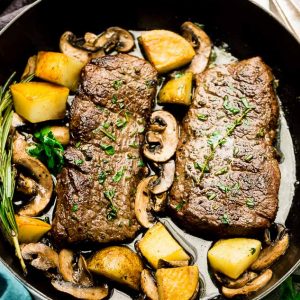 Top view of steak and Potatoes in a white cast iron pan