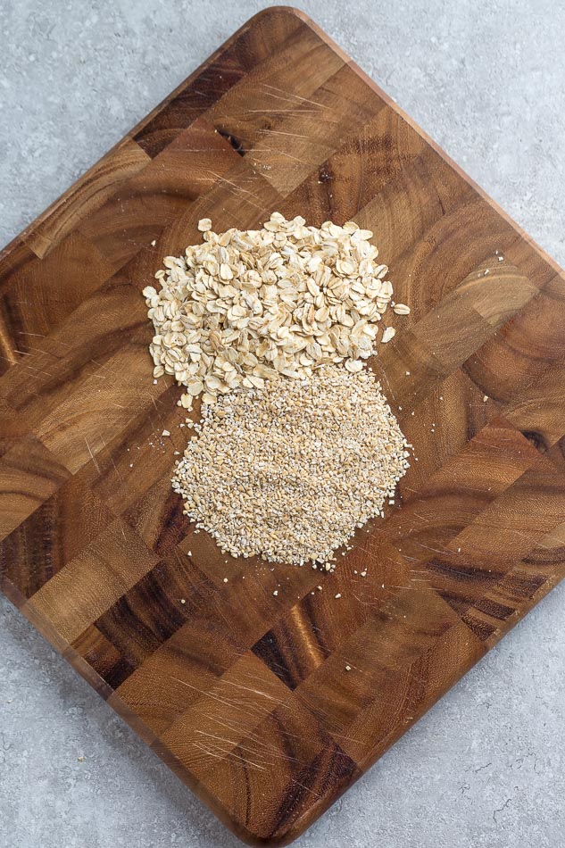 A Pile of Steel Cut Oats Next to a Pile of Rolled Oats on a Cutting Board