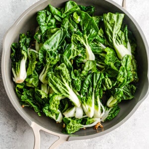 A pile of uncooked bok choy in a large wok