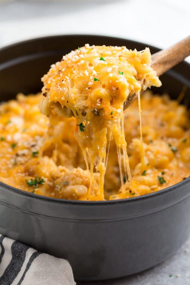 Side view of cheesy macaroni and cheese on top of wooden spoon.